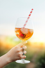 Young woman holding goblet of alcohol cocktail with cherries and striped straw