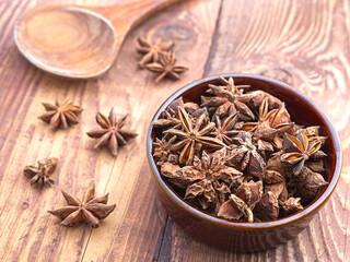 Dried star anise in small brown bowl.