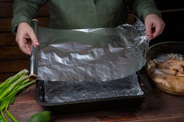 woman's hands line baking foil in two layers on a baking sheet