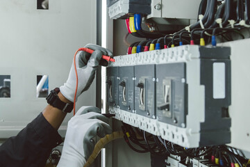 Electrician engineer tests electrical installations and wires on relay protection system.