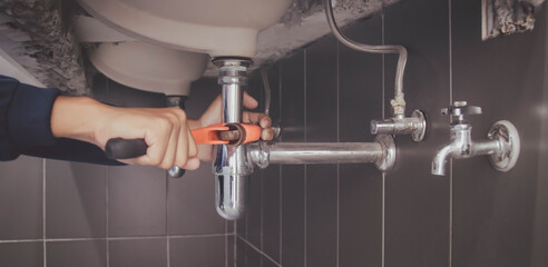 plumber at work in a bathroom, plumbing repair service , fix water plumbing leaks, replace the kitchen sink drain