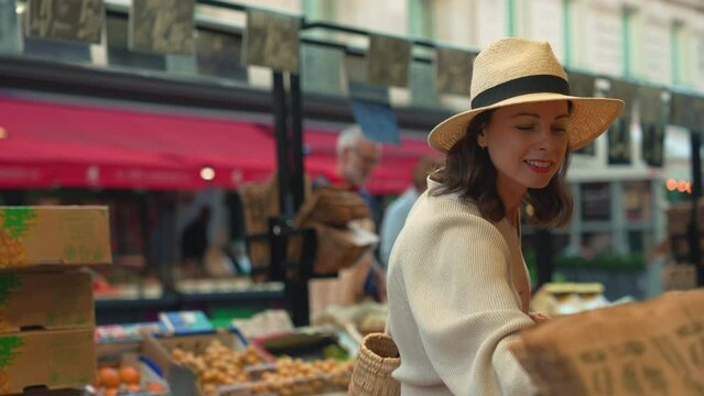 Beautiful girl choosing fruits at the market in Paris