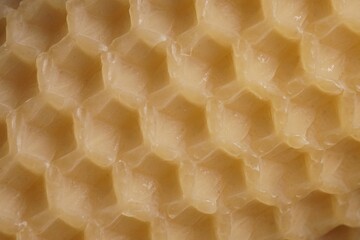 Macro background with an old sheet of natural beeswax; sheet of comb foundation with a hexagonal...