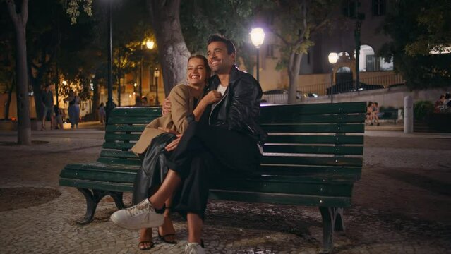 Affectionate couple sitting park cuddling in evening date. Happy spouses resting