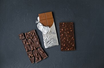 Sweet temptation: two chocolate bars on a dark background. Flat lay, top view. A combination of milk and dark chocolate.