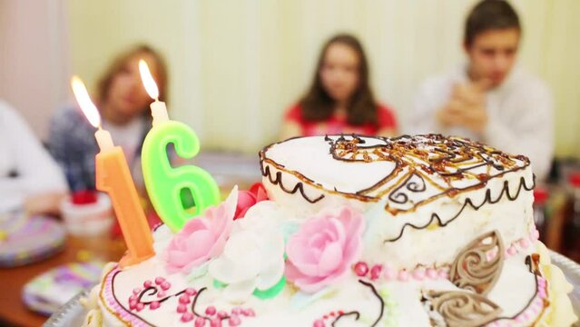Hands hold birthday cake and five teens out of focus