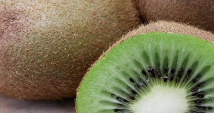 Macro video or extreme close up of three delicious kiwi fruits on a turntable - one has been halved and we can see the green flesh