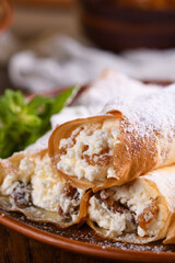 Thin pancakes filled with cottage cheese, honey and raisins, rolled in the form of a tube, sprinkled with powdered sugar, garnished with mint. Festive dish for the pagan Slavic holiday Maslenitsa