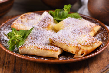 Thin pancakes filled with cottage cheese, honey and raisins, wrapped in an envelope, sprinkled with powdered sugar, garnished with mint. Festive dish for the pagan Slavic holiday Maslenitsa