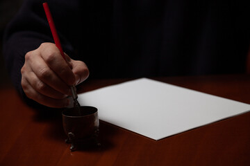 Hand lowers fountain pen into inkwell....