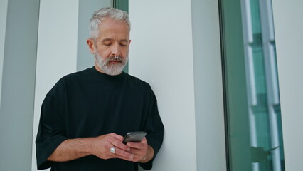 Fototapeta premium Bearded adult texting mobile phone on street. Focused grey hair senior using