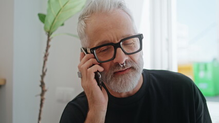 Bearded senior speaking mobile phone closeup. Smiling creative manager discuss