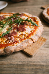 Delicious hot meat pizza with prosciutto and salami on a wooden table. High quality photo