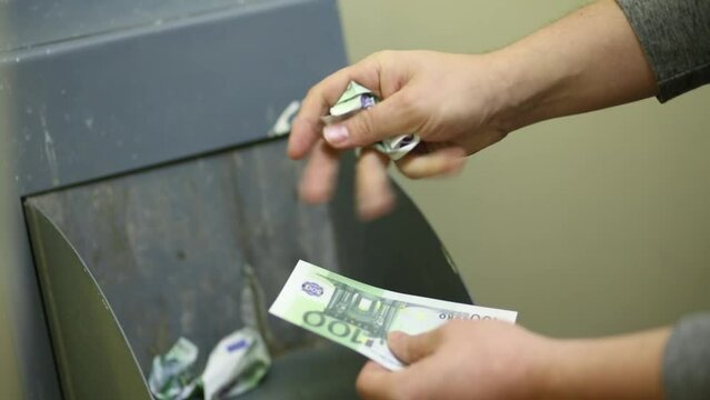 Man crumples 100 euro bills and throwing them in the garbage disposal