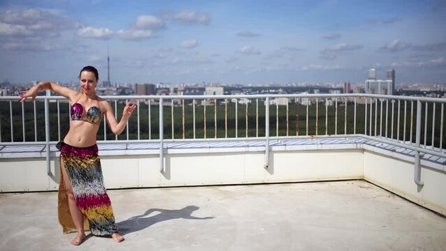 Woman dancing in Indian style on roof of tall building.