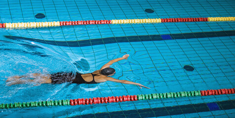 Sportswoman, a professional swimmer using breaststroke drills during a swim training session to...