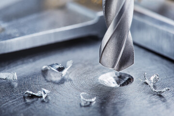 metal drill bit make holes in steel billet on industrial drilling machine