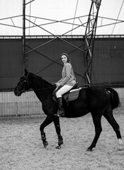 Woman Riding on the Back of a Black Horse. A woman confidently rides on the back of a majestic...