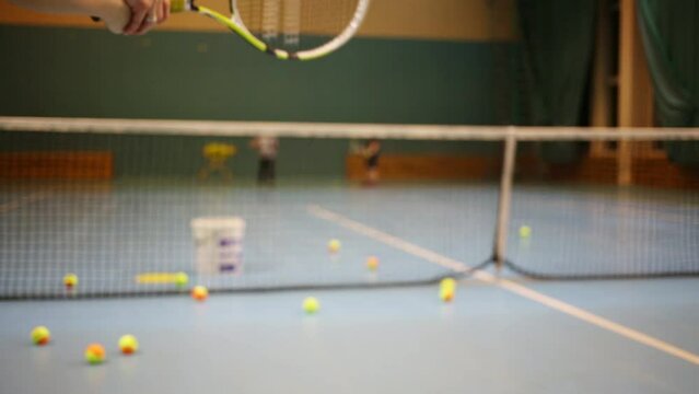 Hands of coacher training to girl to hold racket. 