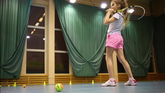 Girl learns to beat off balls during tennis training