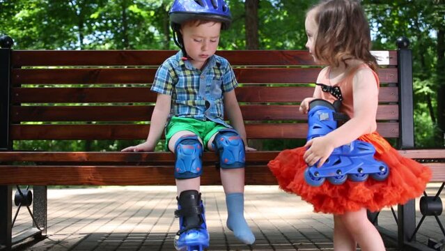 Little boy sits on bench and girl helps to him in park