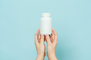 Woman's hand holds white plastic tube. Bottle for pill, capsule or supplement. Product branding mockup - obrazy, fototapety, plakaty