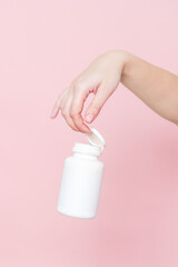 Obraz na płótnie Canvas Blank white plastic tube in hand on pink background. Cosmetics beauty mockup for product branding