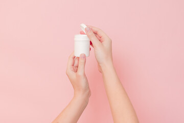 Hand holding plastic bottle on pink background. Cosmetics beauty mockup for product branding