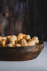Close up of in shell peanuts on a wooden plate on dark background