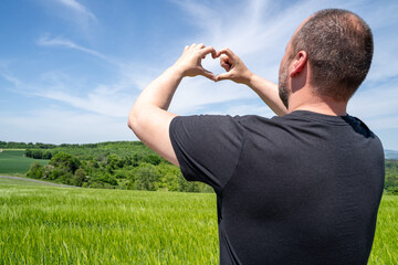 Man makes heart shape with his fingers in the landscape