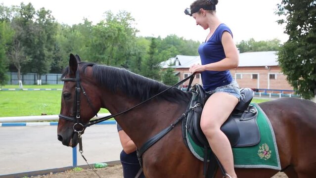 Smiling woman in shorts lies on horse with emblem on seat