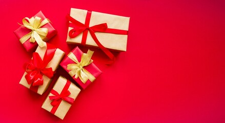 On a red background there are gifts in festive packaging with a red bow. Holidays concept, Valentine's day, Christmas. Flat lay, top view. Space for copying text

