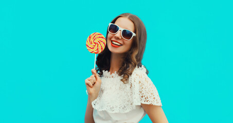 Portrait of happy caucasian smiling young woman holding colorful lollipop wearing white sunglasses...
