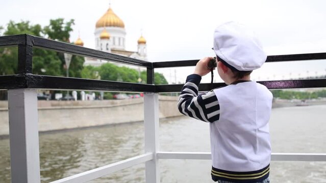 Boy dressed as captain looks through binoculars at Cathedral