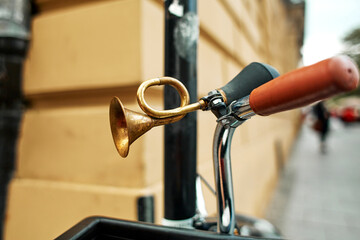 Close-up of a brass retro horn on a bicycle handlebar.