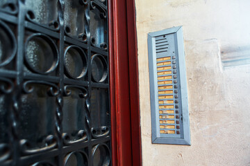 An old intercom with the names of the tenants is built into the wall at the front door of an old...