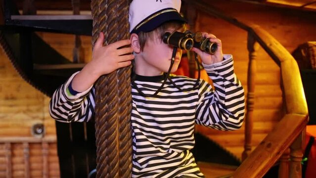 Boy sits on wooden spiral staircase and looking through binoculars