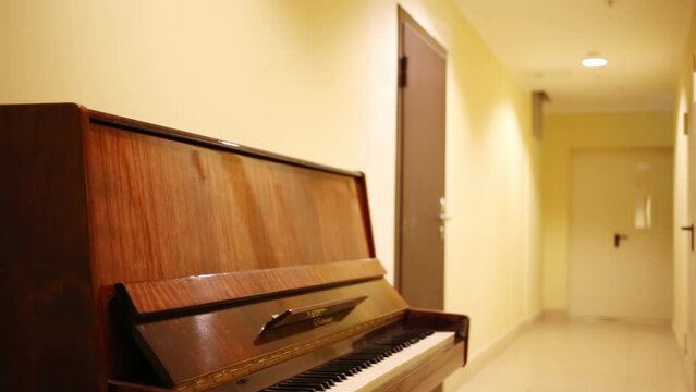The old brown lacquered piano standing in a corridor