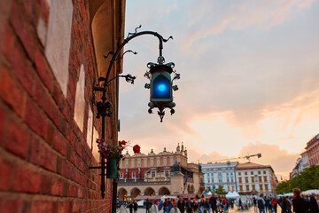 An old blue lantern made of handmade metal hangs on a brick wall in the historic streets of Krakow.