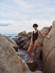 Sensual Lady Relaxing on Sun-Kissed Beach: Attractive Caucasian Female in White Swimsuit, Posing on Orange Stone near the Sexy Sea Water.