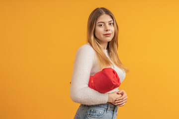 Young woman holding a red cloth sling with her arm through it against a yellow background