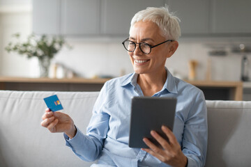 senior woman shopping using digital tablet and credit card indoors