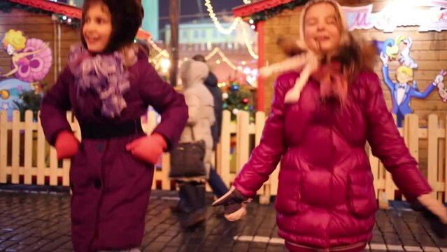 Two girls dance at street at annual Christmas Fair of GUM 