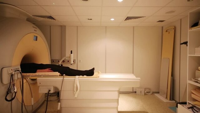 The patient lies on MRI scanner bed in the room 