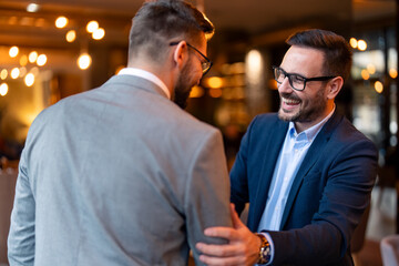Two smiling confident male business partners at business meeting in a co-working office, finishing up a meeting or setting goals, sharing productive ideas.