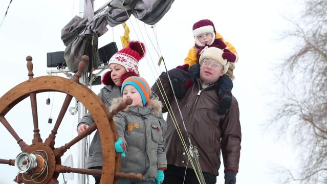 Mother, father and two childrens play with steering wheel at winter