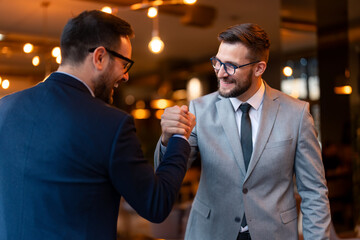 Excited young adult businessman, greeting a new member of his team. Happy adult bearded company...