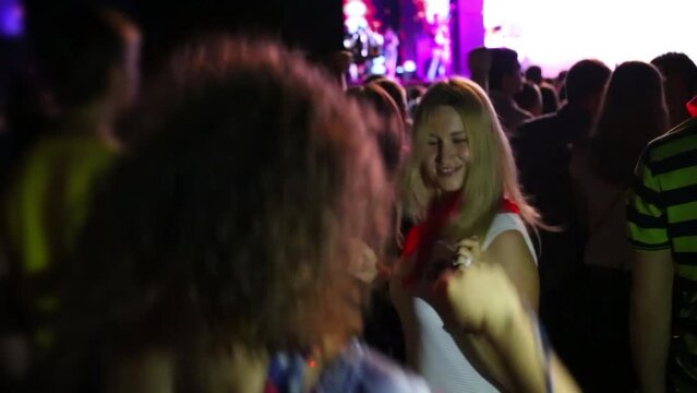 Two happy women dance among many people in night club