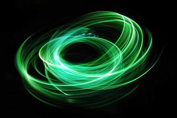A beautiful, bright light swirl of green color. Futuristic light painting on a black background. Round light circles