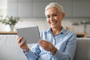Fototapeta na wymiar Portrait Of Happy Mature Lady Using Digital Tablet Browsing Internet